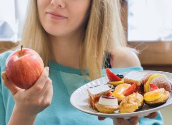选择健康苹果的妇女而不是垃圾点心作为食物掉剪卡路口